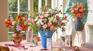 An image of a lady placing a vase full of flowers onto a table